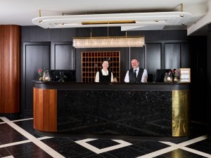 Es ist die Rezeption mit zwei Mitarbeitern des Hotel Mohren in Oberstdorf zu sehen.