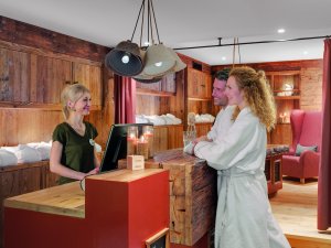 Es sind zwei Gäste des Hotel Oberstdorf an der Rezeption des Wellness-Bereichs zu sehen.
