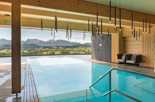 Bild des Infinitypools des Hotels mit Blick ins Grüne und auf die Berge im Allgäu.