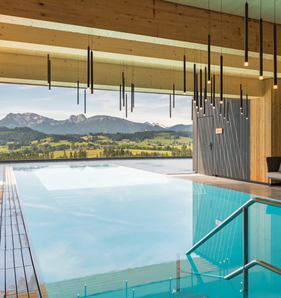 Bild des Infinitypools des Hotels mit Blick ins Grüne und auf die Berge im Allgäu.