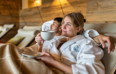 Ein Paar liegt auf einer der gemütlichen Liegen im Wellnessbereich des Biohotel Eggensberger in Füssen / Hopfen am See