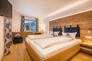 Einblick in eines der modern eingerichteten Zimmer mit gemütlichem Doppelbett und Balkon im Ferienhotel Starennest in Oberstaufen