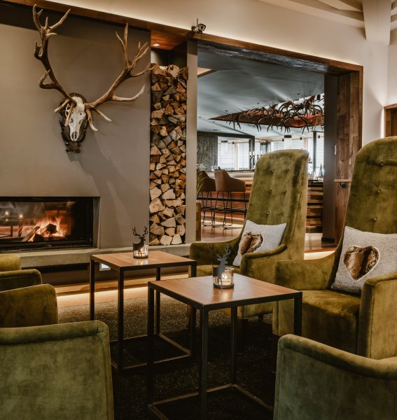 Wunderschöne und gemütliche Lobby im Hotel Bergkristall, mit Blick auf den Kamin mit Kaminfeuer und im Hintergrund die Hansi-Bar.