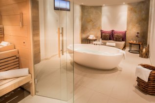 Eine gefüllte große freistehende Badewanne die zum Entspannen einlädt im Hotel Exquisit in Oberstdorf