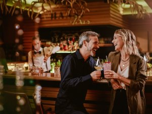 Ein Paar genießt Zweisamkeit und einen Cocktail an der Bar im Bergkristall - Mein Resort im Allgäu in Oberstaufen