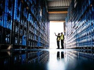 Zwei Mitarbeiter stehen in der Lagerhalle der Allgäuer Alpenwasser GmbH in Oberstaufen