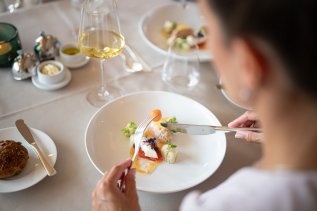 Eine Dame isst im Hotel Exquisit in Oberstdorf eine ansprechend angerichtete Speise