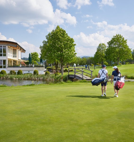 Zwei Gäste vom Hanusel Hof in Weitnau sind mit ihrem Golfequipment auf dem Weg zurück zum Hotel
