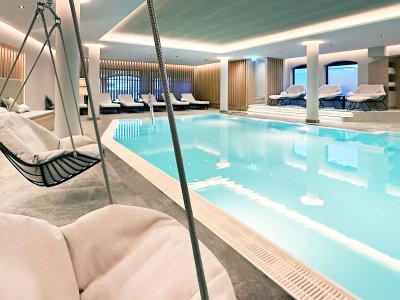 Blick auf den neuen Innenpool und Wellnessbereich des Bayerischen Hofs in Oberstaufen mit bequemen Liegemöglichkeiten.