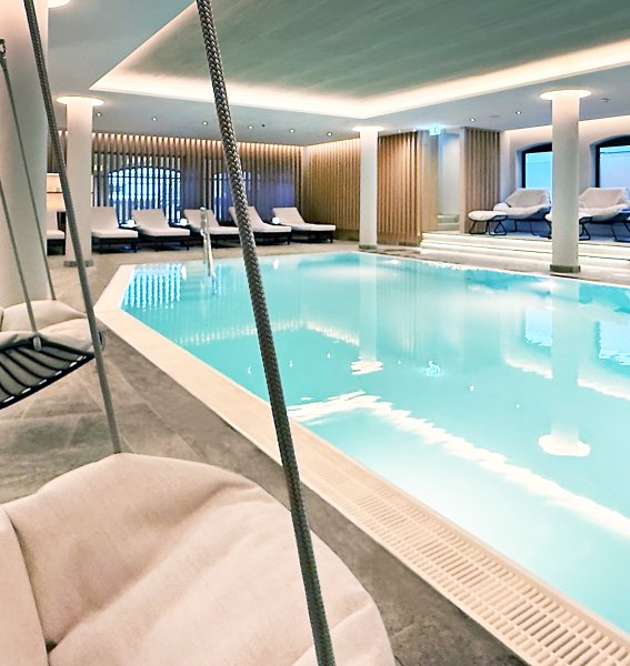 Blick auf den neuen Innenpool und Wellnessbereich des Bayerischen Hofs in Oberstaufen mit bequemen Liegemöglichkeiten.