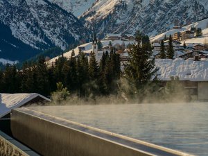 Ausblick auf die verschneiten Berge und den Infinitypool im Ifen Hotel Kleinwalsertal