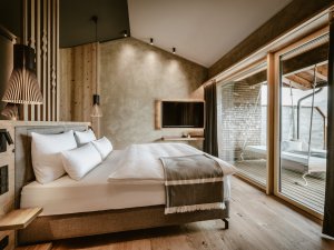 Einblick in eines der Zimmer im Bergkristall - Mein Resort im Allgäu in Oberstaufen mit Blick auf ein Doppelbett das zum Balkon hin ausgerichtet ist