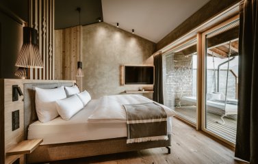 Bergkristall Mein Resort im Allgaeu Zimmer Einblick in eines der Zimmer im Bergkristall - Mein Resort im Allgäu in Oberstaufen mit Blick auf ein Doppelbett das zum Balkon hin ausgerichtet ist