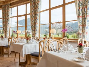 Einblick in den Wintergarten im Restaurant vom Best Western Plus Hotel Alpenhof in Oberstdorf mit tollem Rundumblick auf die grüne und bergige Umgebung