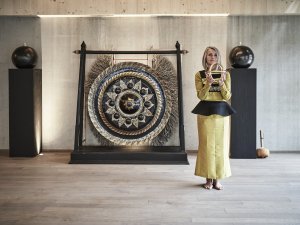 Die Senior-Hotelchefin steht im Yogaraum im HUBERTUS Mountain Refugio Allgäu in Balderschwang und hält einen Gegenstand in beiden Händen