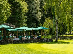 Eines der Restaurants im Sonnenalp Resort in Ofterschwang von Außen mit Blick auf die Terrasse und Bäume darum