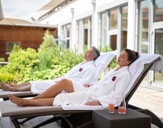 Ein Paar entspannt sich auf den Liegestühlen im Wellnessbereich des Hotels Exquisit in Oberstdorf.