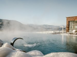 Blick auf den Infinitypool und die verschneite Umgebung im Bergkristall - Mein Resort im Allgäu in Oberstaufen im Winter
