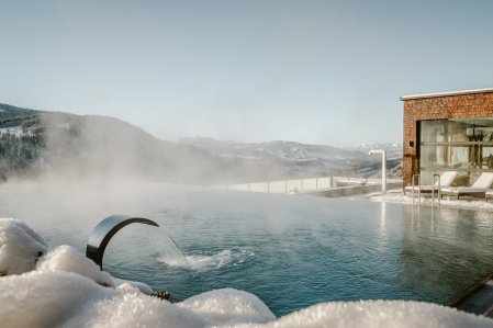 Blick auf den Infinitypool und die verschneite Umgebung im Bergkristall - Mein Resort im Allgäu in Oberstaufen im Winter