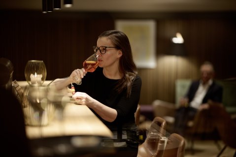 Eine Dame genießt einen Aperitif an der Bar des Hotels Bannwaldsee in Halblech.