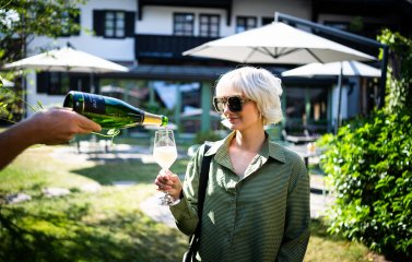 Eine Frau genießt ein Glas Wein auf der Terrasse im Das Freiberg Romantikhotel in Oberstdorf.