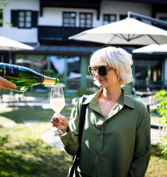 Eine Frau genießt ein Glas Wein auf der Terrasse im Das Freiberg Romantikhotel in Oberstdorf.