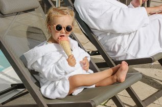 Ein kleiner Gast genießt eine Kugel Eis im Liegestuhl im Panoramahotel in Oberjoch.