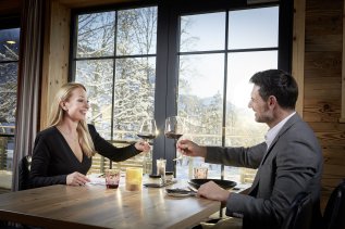 Ein Paar genießt ein Glas Wein im Restaurant der Alpin Chalets in Oberjoch.