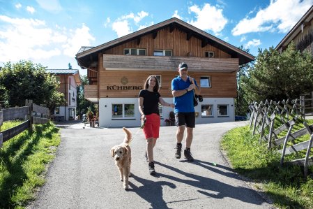 Gäste auf einem Spaziergang mit Hund um das Hotel Kühberg in Oberstdorf.