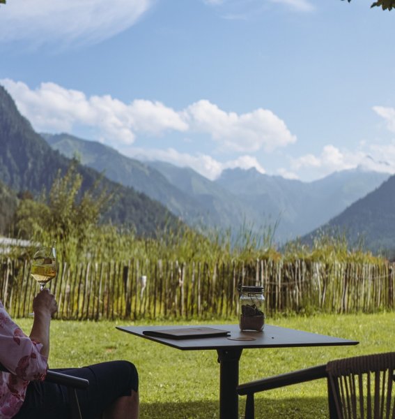 Eine Dame genießt ein Glas Wein mit Blick auf die Alpen im Hotel Kühberg in Oberstdorf.