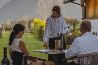 Die Gastgeberin des Hotels Kühberg in Oberstdorf serviert Gästen einen Wein auf der Terrasse.