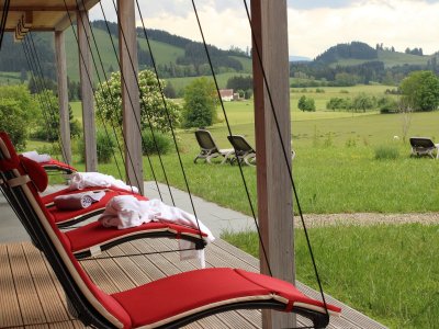 Hängende Liegestühle auf der Terrasse des Wellnessbereichs mit Blick auf die Natur im Sontheim's Naturhotel & Spa in Maierhöfen.