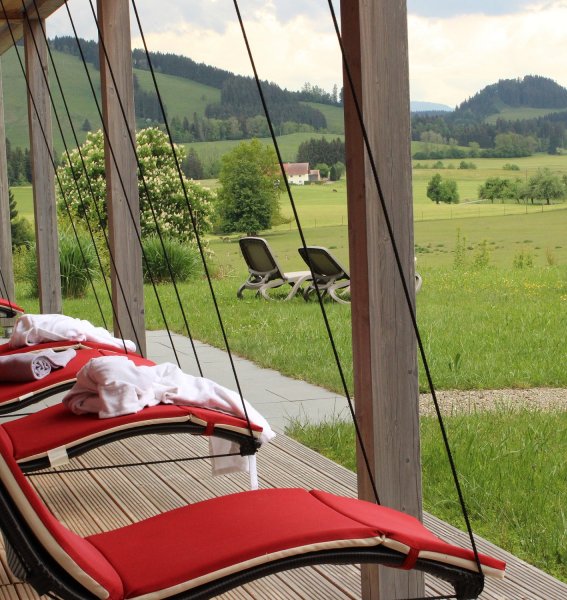 Hängende Liegestühle auf der Terrasse des Wellnessbereichs mit Blick auf die Natur im Sontheim's Naturhotel & Spa in Maierhöfen.