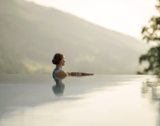 Eine Dame genießt den Ausblick im Außenpool im Hotel Prinz-Luitpold-Bad in Bad Hindelang.