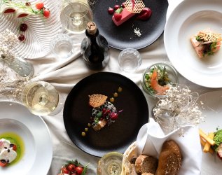 Blick von oben auf mehrere Gourmet-Teller mit schön angerichteten Speisen.