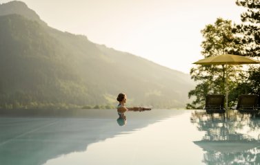 Eine Dame genießt den Blick auf die Berge im Außenpool im Hotel Prinz-Luitpold-Bad in Bad Hindelang.