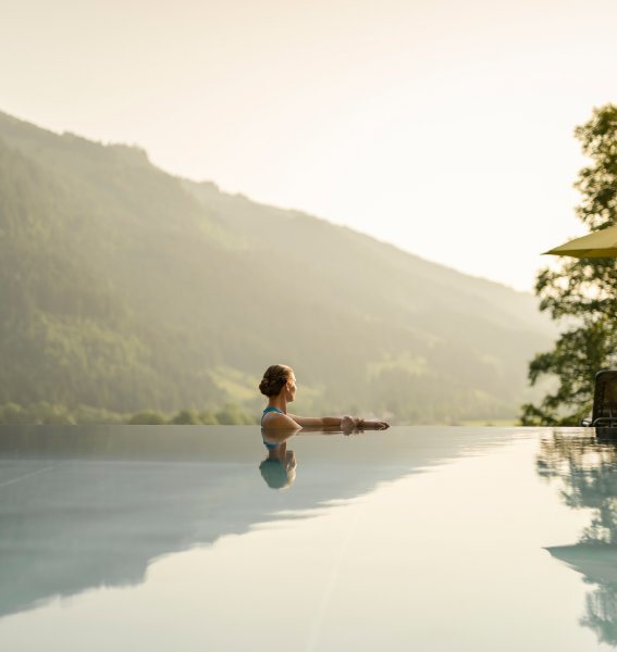 Eine Dame genießt den Blick auf die Berge im Außenpool im Hotel Prinz-Luitpold-Bad in Bad Hindelang.