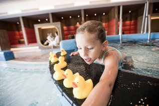 Ein Kind spielt mit Badeenten im Pool im Familotel Allgäuer Berghof in Ofterschwang