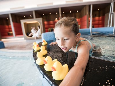 Ein Kind spielt mit Badeenten im Pool im Familotel Allgäuer Berghof in Ofterschwang