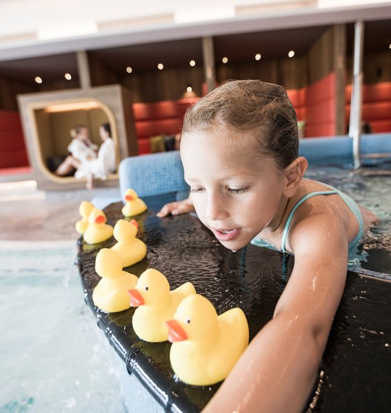 Ein Kind spielt mit Badeenten im Pool im Familotel Allgäuer Berghof in Ofterschwang