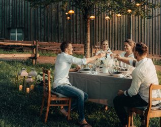 Vier Gäste stoßen mit einem Glas Wein auf der Terrasse der Alpzitt Chalets in Burgberg im Allgäu an.