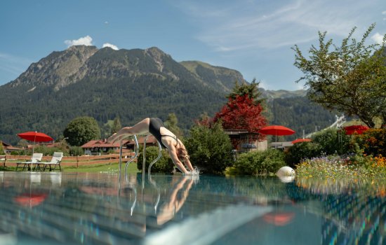 Eine Dame springt in den Außenpool im Sommer im Hotel Franks in Oberstdorf.