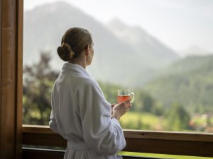 Eine Dame trinkt einen Tee im Bademantel auf dem Balkon im Hotel Prinz-Luitpold-Bad in Bad Hindelang.