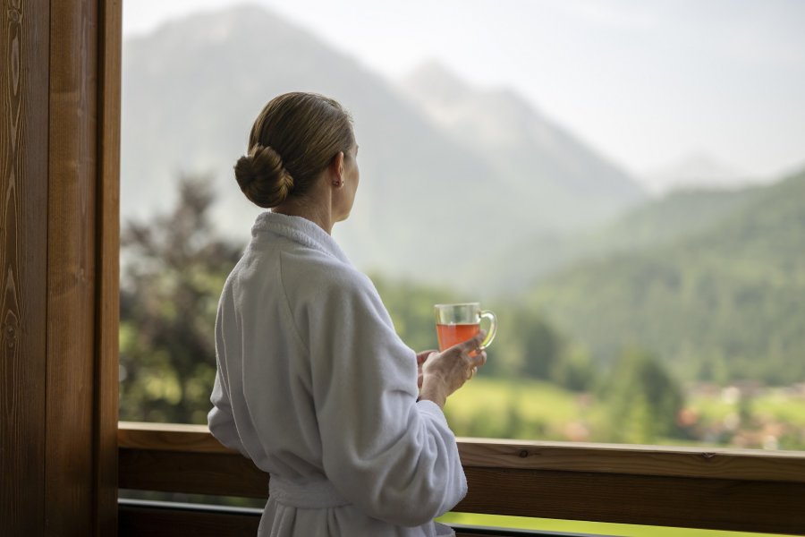 Eine Dame trinkt einen Tee im Bademantel auf dem Balkon im Hotel Prinz-Luitpold-Bad in Bad Hindelang.
