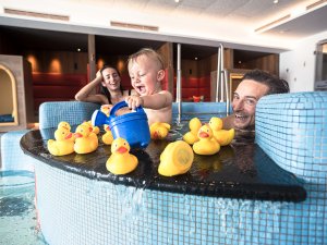 Eine Familie spielt mit ihrem Baby im Kinderpool mit Quietsche-Enten im Familotel Allgäuer Berghof in Ofterschwang.