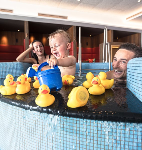 Eine Familie spielt mit ihrem Baby im Kinderpool mit Quietsche-Enten im Familotel Allgäuer Berghof in Ofterschwang.