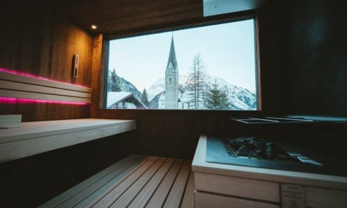 Einblick in die Sauna im Winter mit Blick auf den Kirchturm im Hotel Tradizio im Kleinwalsertal.