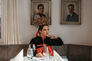 Eine Dame in traditioneller Tracht sitzt am Tisch im Restaurant im Hotel Tradizio im Kleinwalsertal.