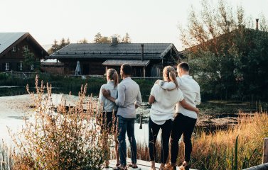 Zwei Pärchen stehen auf einem Steg am See und umarmen sich in den Alpzitt Chalets im Dorf in Burgberg.