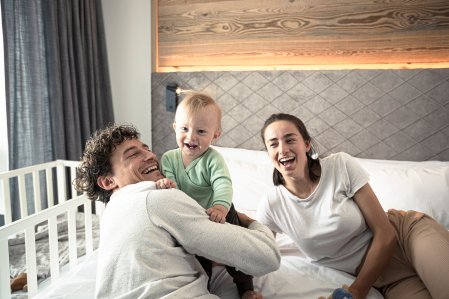 Eine Familie mit Baby albert herum in einem Zimmer im Familotel Allgäuer Berghof.